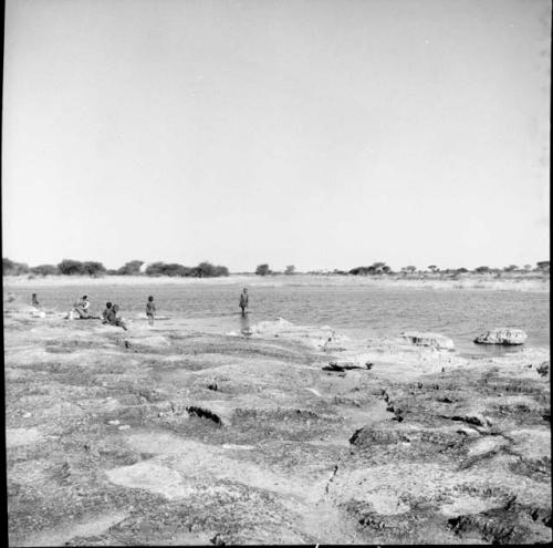 People standing and sitting at the edge of a pan, distant view