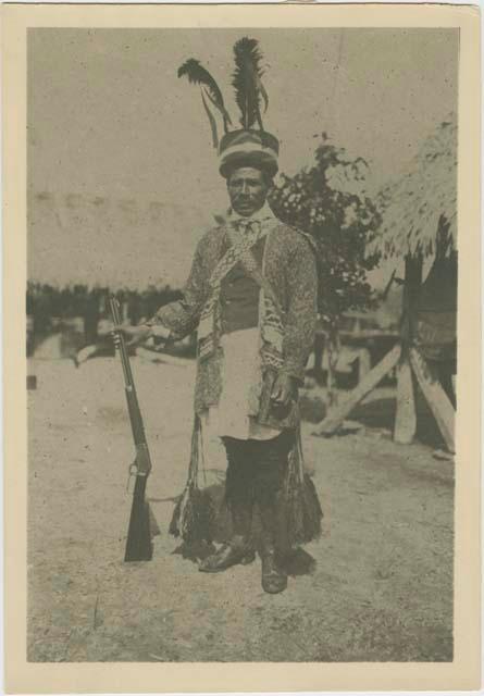 Muskogean Seminole man with gun wearing feathered cap