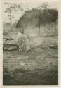 Woman sitting beside fire in camp