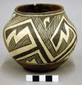 Small pottery vessel. Base brownish red, cream slip with dark brown design