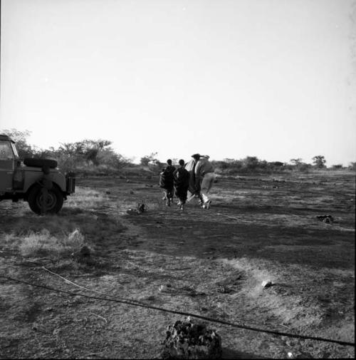 Two women walking with John Marshall near the expedition Land Rover