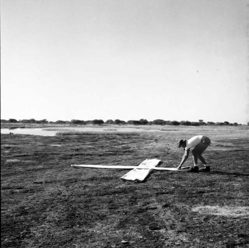 Nicholas England laying out white strips of cloth for an airplane landing guide