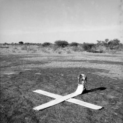 Nicholas England laying out white strips of cloth for an airplane landing guide