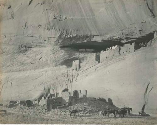 People and horses with cliff dwelling