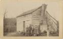 Man and boys standing in front of a cabin