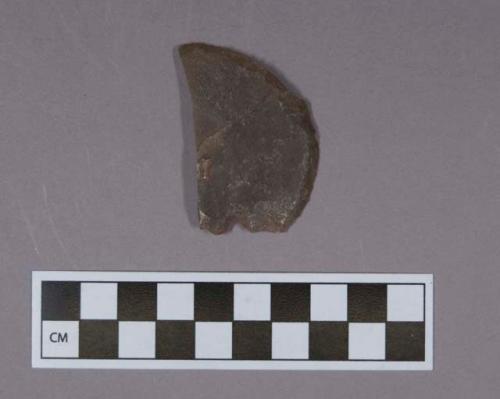 Fragment of a flat, semi-circular flint end scraper made on a flake