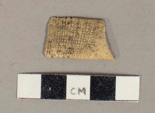 Worked bone fragment, flat, broken at both ends, notches along sides, crosshatch pattern engraved on surface