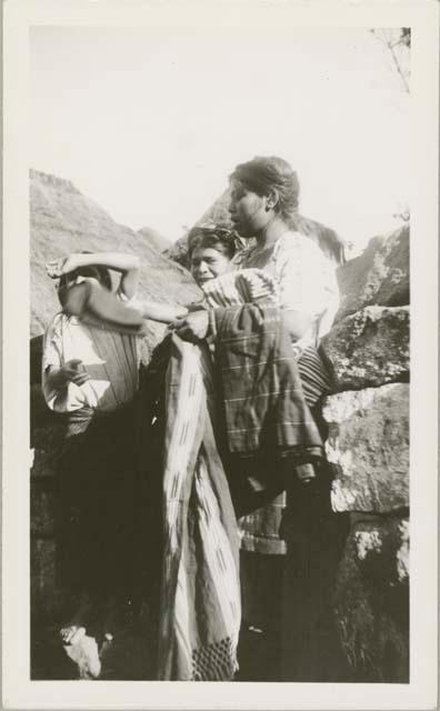 Three people in frame, one holding fabrics