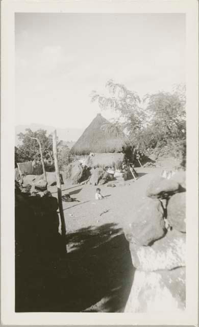 Atitlan houses with thatched roofs, child sitting on ground, center frame