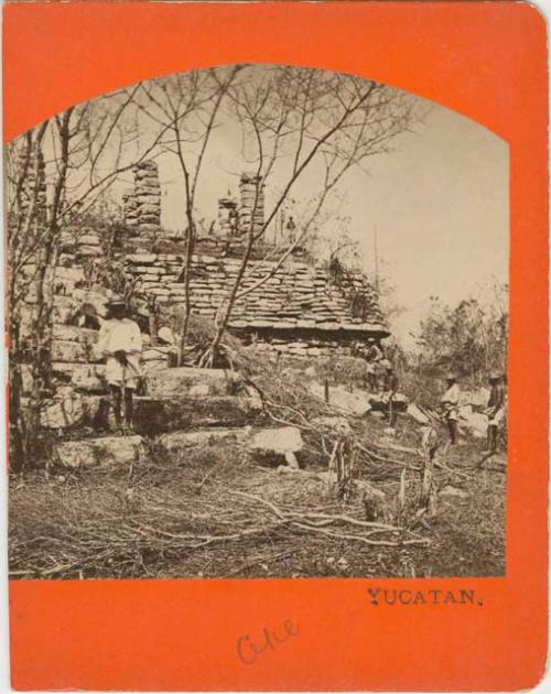 Men standing on top of, and below, building ruins in Ake