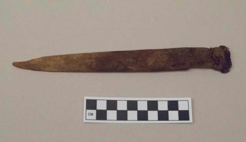 Wooden implement with pointed end other end is wrapped in cordage and pitch (?).