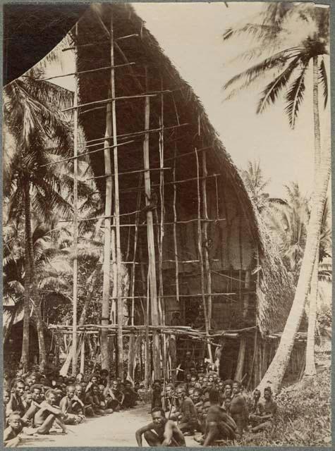 Group of men sitting in front of a large building