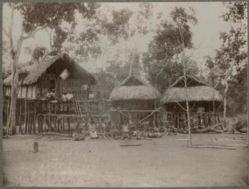 Group of people in front of thatched buildings