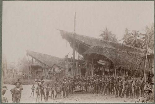 Group of people in front of thatched buildings