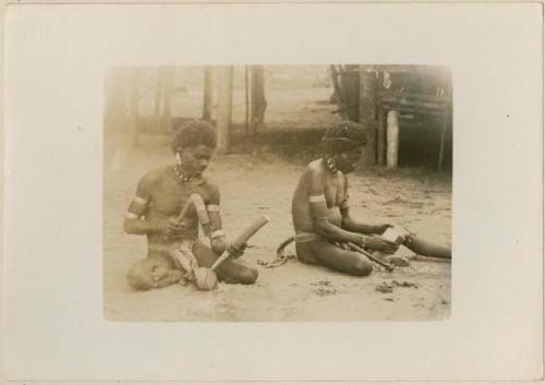 Men making a head rest and a sago mallet