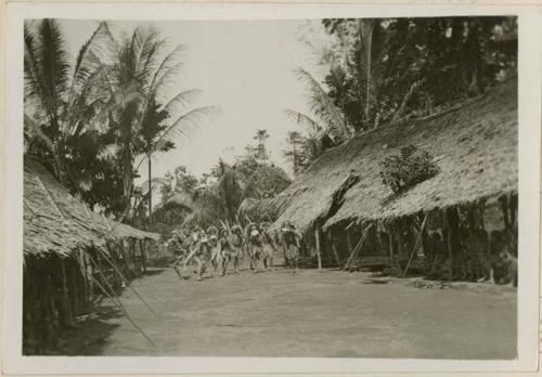 Group of men dancing between rows of houses