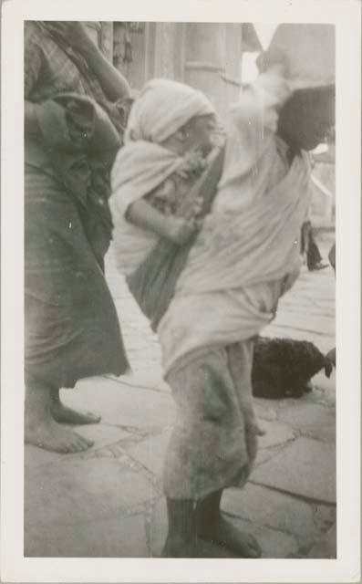 Individual carrying child on their back, possibly in Chichicastenango