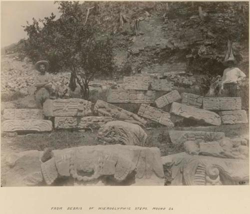 Two men standing among sculptures from debris of hieroglyphic steps, Mound 26