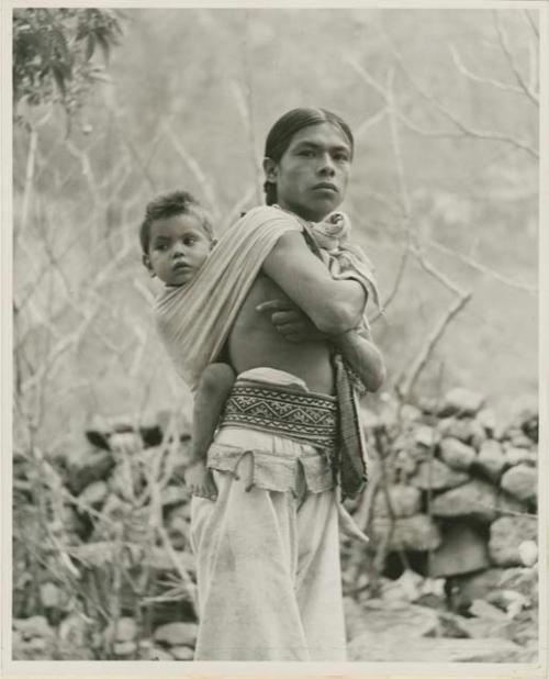 Huichol father carrying child on his back