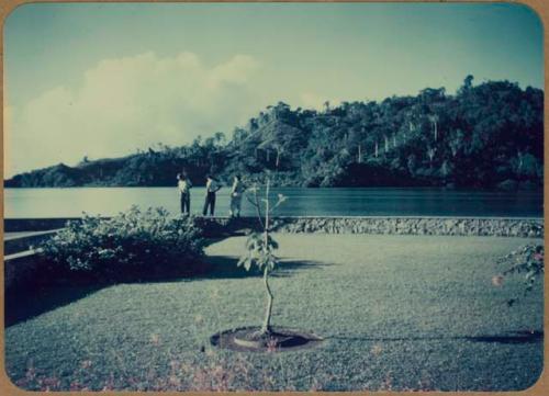 Three people standing and looking at water