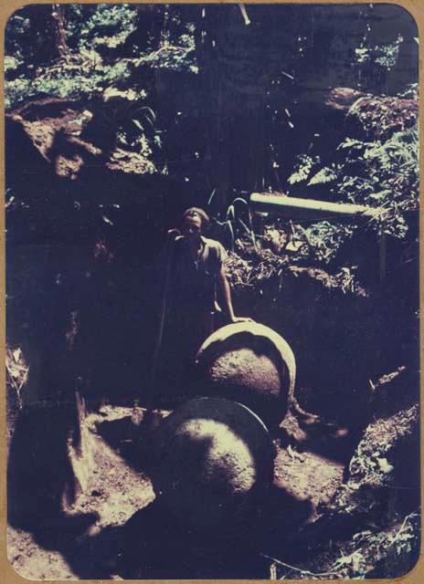 Man standing in excavation unit with two stone balls