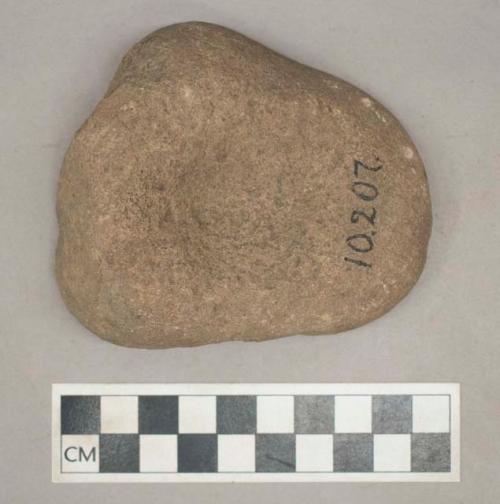 Ground stone, pitted grinding stone fragment