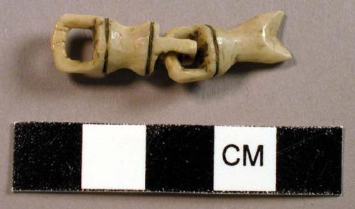 Carved ivory, possibly fish, linked body and tail.