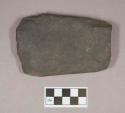 Ground stone, adze fragment, pecked and chipped at edge, ground indentations on both sides
