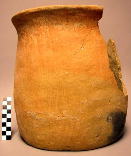 Complete ceramic jar, red with fireclouding, plain, sherds missing.
