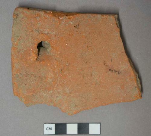 Red ceramic rooftile fragment, nail hole present