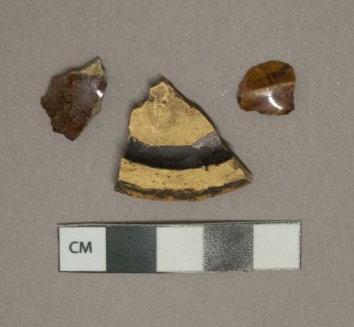 Mottled brown lead glazed earthenware vessel body and base fragments, buff paste, likely rockingham type