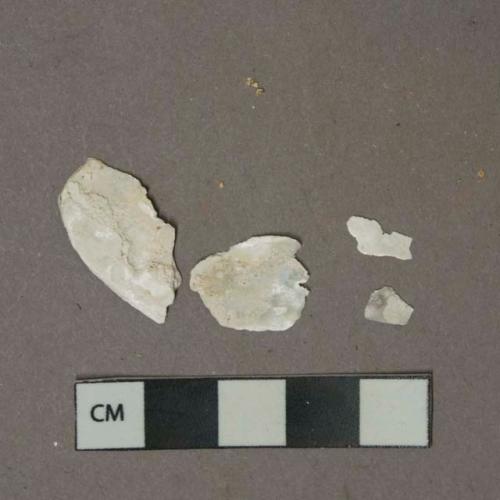 White unidentified shell fragments, heavily degraded