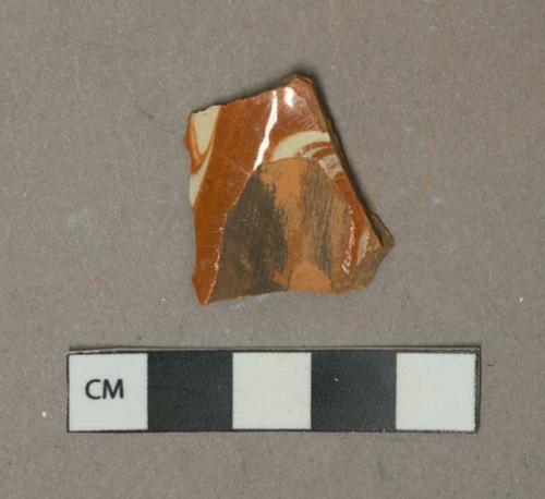 Cream on red marbled slip decorated redware vessel body fragment, likely North Italian slipware