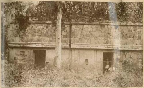 Ruined city of Chunkatzin, men sitting or standing around structure covered with vegetation