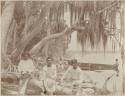 Three men in foreground, woman in background, man in canoe, on Sacred Island near Silbituk