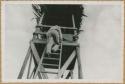 Man climbing ladder on tower built for movie camera