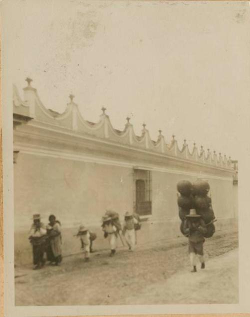 People carrying bundles in front of building