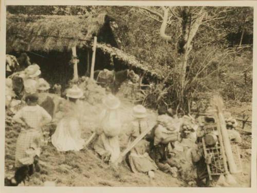 Group in front of a thatched-roof structure