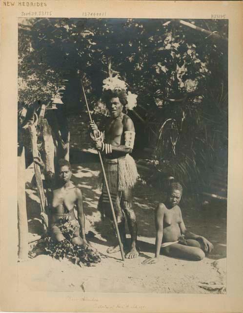 Man standing and two women sitting