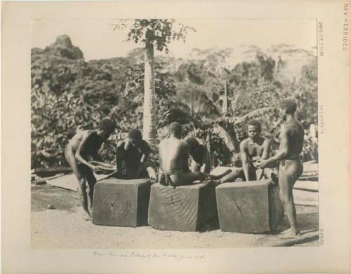 Men sitting on large blocks of wood