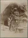 Man and boy with wooden statue of a man, in front of a house