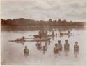 Boys and girls in lagoon with canoes