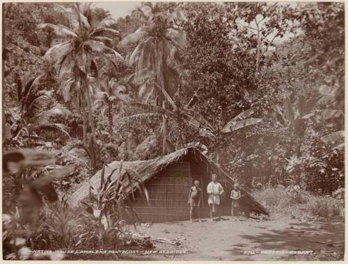 Man and two boys standing in front of a house