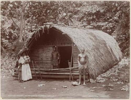 Two men, woman and two children in front of a house at Tegue