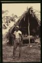 Don Polo standing in front of thatched shelter