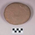 Ground stone, flat ovoid stone with indentation on one side, possible pounding stone