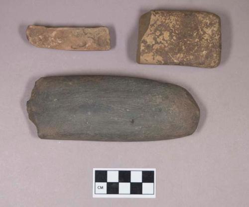 Ground stone, worked stone fragment, likely adze fragment; ground stone, rectangular stone fragments, one with possible red ochre staining