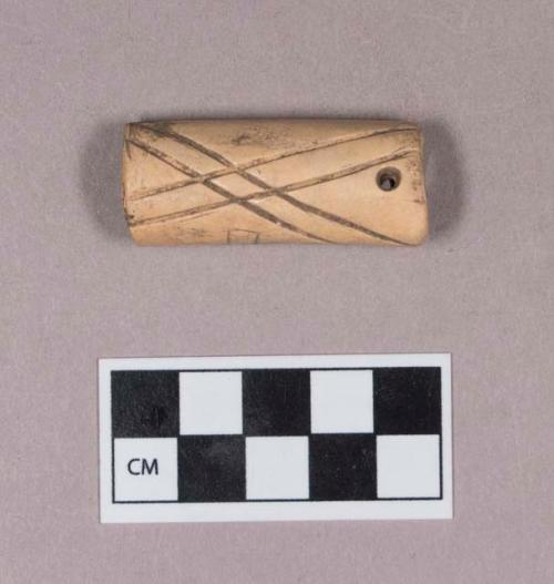 Cut and worked animal bone tube, two perforations at one end, incised linear decoration, less deeply incised design on one side