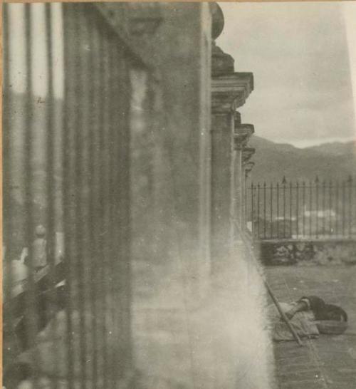 Woman sleeping next to wrought-iron and stone fence