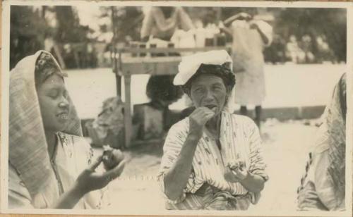 Two women eating in front of street vendor